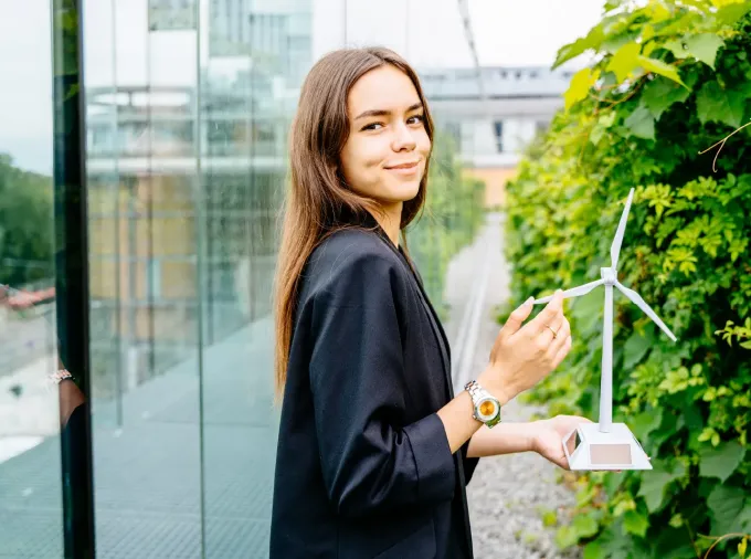 Young professional woman outside holding a small model of a wind turbine.