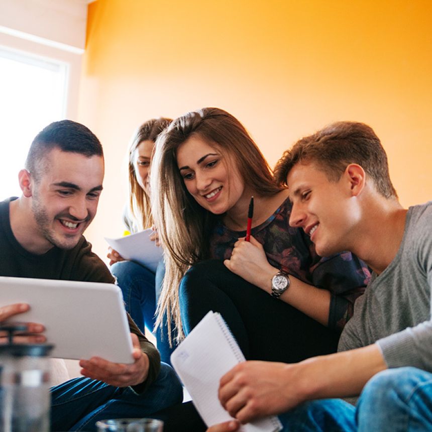 three young adults looking at a tablet.